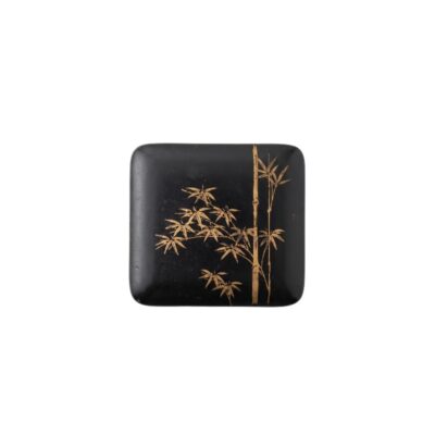 A small square box with rounded corners and a dark black finish, featuring a delicate gold-coloured painted design on the top depicting bamboo stems and leaves; available for hire for events, advertising, films and TV series