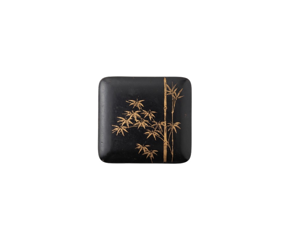 A small square box with rounded corners and a dark black finish, featuring a delicate gold-coloured painted design on the top depicting bamboo stems and leaves; available for hire for events, advertising, films and TV series