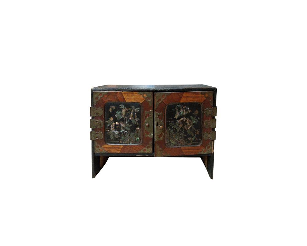 A horizontal wooden cabinet, featuring two front doors decorated with dark panelling and iridescent floral inlays; available for hire for events, advertising, films and TV series