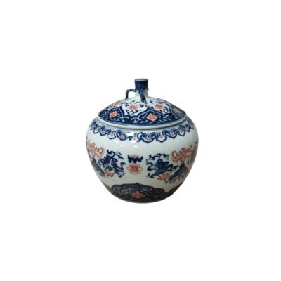 A globular porcelain jar distinguished by its delicate two-tone decoration, combining cobalt blue with reddish or orange hues. It features floral motifs and stylised abstract forms harmoniously distributed across both the main body and the lid, which has a distinctive central finial. Hire for events, advertising, films and TV series