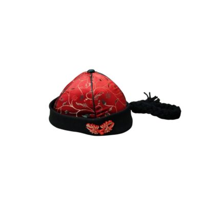 A traditional conical hat with panels of red silk fabric embroidered with gold and dark floral motifs, characterised by a black brim decorated with a red bow and a long plait; available for hire for events, advertising, films and TV series
