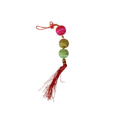 A traditional pendant ornament with a vertical design, featuring three spheres covered in shiny thread in shades of fuchsia, gold and light green, a decorative knot at the top and a tassel made of red threads at the bottom. Available for hire for events, advertising, films and TV series.