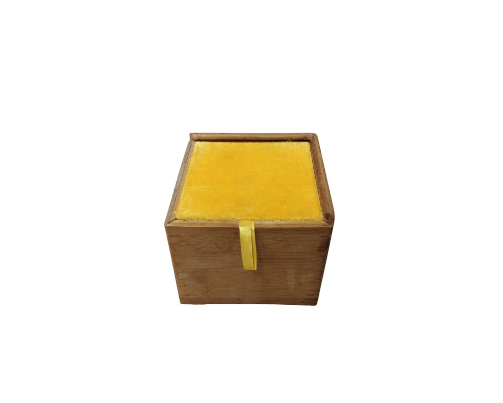 A small, square wooden box in natural tones, featuring a padded lid lined with bright yellow fabric and a small vertical ribbon in the same shade to make it easier to open; available for hire for events, advertising, films and TV series
