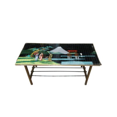 A rectangular coffee table characterised by a top surface composed of small tiles or tesserae forming a traditional Japanese landscape mosaic, including figures in kimonos, a snow-capped mountain and a torii gate, supported by a metal frame with reinforcing cross-bars at the base. Available for hire for events, advertising, films and TV series