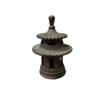 Objeto metálico con una estructura detallada que recrea la forma de una pagoda tradicional de varios niveles. La pieza presenta un diseño calado y relieves decorativos, funcionando como un pebetero para incienso. Es una pieza artesanal con una estética oriental distintiva, ideal tanto para uso ceremonial como elemento decorativo de gran valor visual. alquiler para eventos, publicidad, peliculas y series