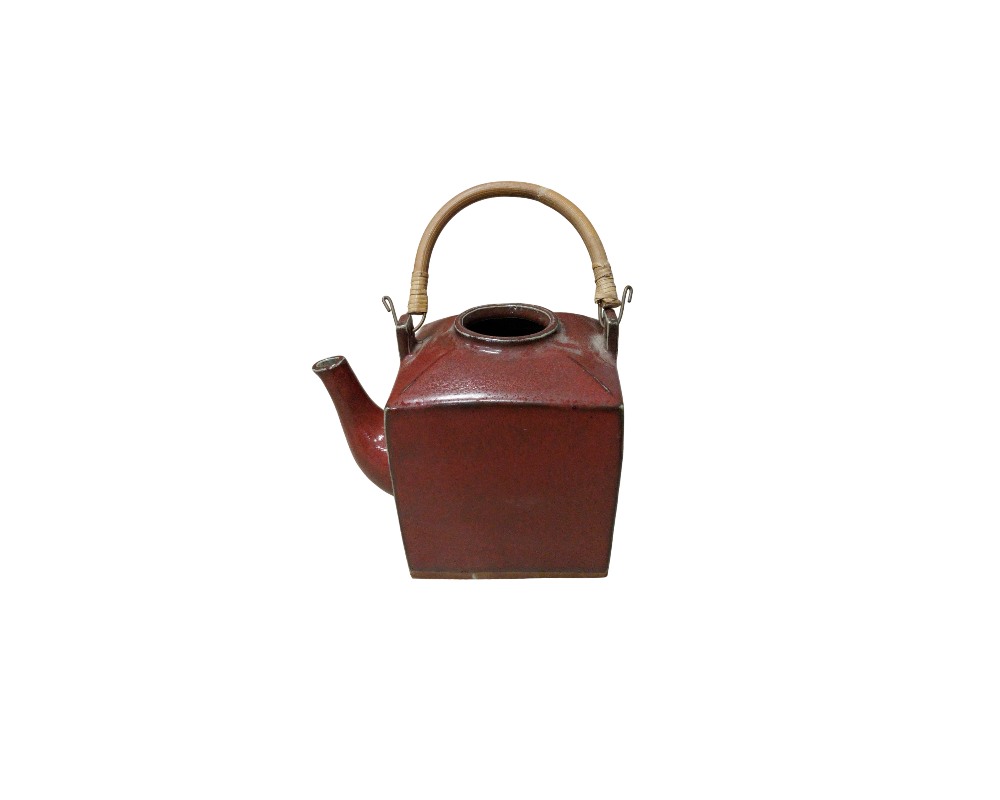 tetera de cerámica con un cuerpo de diseño cúbico y un acabado esmaltado en tonos rojizos oscuros y texturizados alquiler para eventos, publicidad, peliculas y series