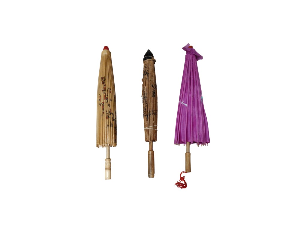 The set includes three small, traditional Oriental-style parasols or umbrellas in their closed position, with wooden frames and paper or fabric covers, featuring decorative printed designs and a variety of colours, including natural tones and purple. Available for hire for events, advertising, films and TV series.