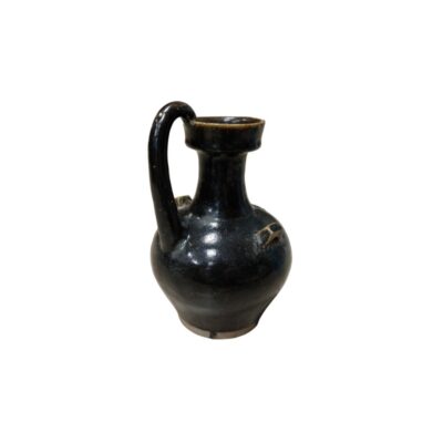 a ceramic jug with a globular body and a glazed finish in dark, glossy shades, characterised by a slender neck, a prominent vertical handle extending from the shoulder to the rim, and small side handles or reinforcing loops. Hire for events, advertising, films and TV series