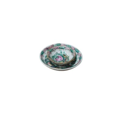 The set comprises a small cup and matching saucer, crafted from fine porcelain. The design features delicate floral and botanical motifs in shades of pink and green, rendered in a style reminiscent of traditional porcelain. Available for hire for events, advertising, films and TV series.