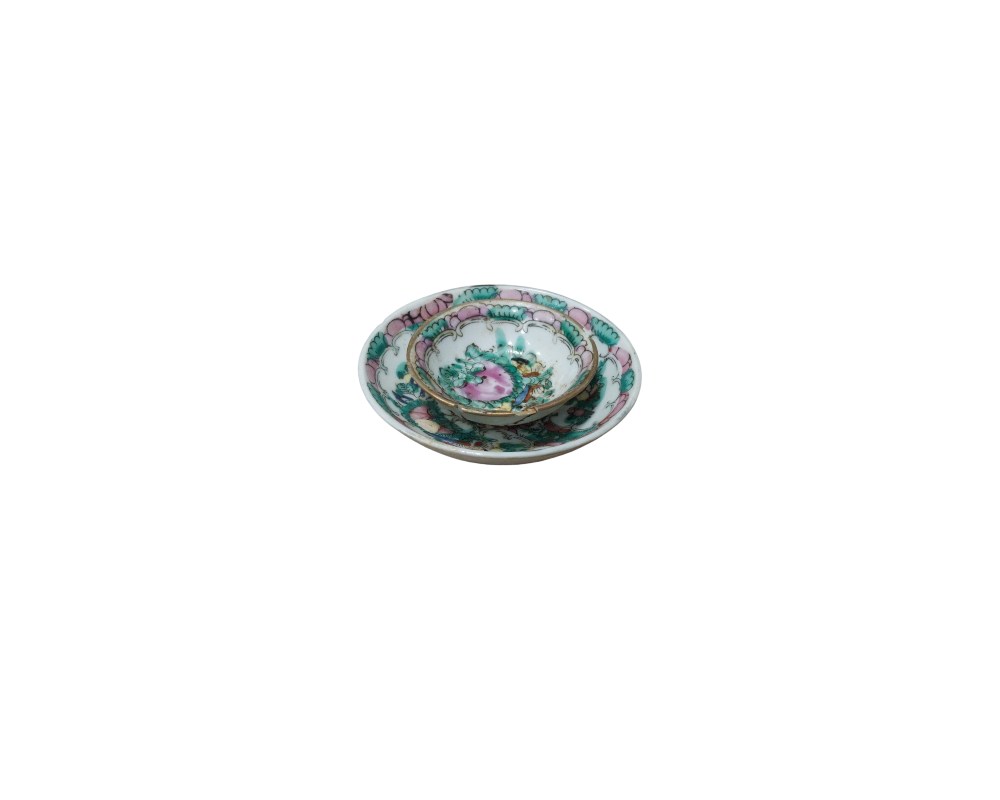 conjunto consta de una pequeña taza y su platillo a juego, elaborados en porcelana fina. El diseño se caracteriza por delicados motivos florales y botánicos en tonos rosados y verdes, ejecutados con un estilo que evoca la porcelana tradicional alquiler para eventos, publicidad, peliculas y series