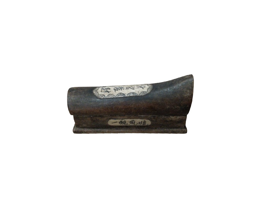 A small object with a curved profile and a rectangular base, made from a dark material with an antique appearance, featuring decorative inlays with calligraphic inscriptions. Its small size confirms its function as a wrist rest, a desk accessory traditionally used by calligraphers to raise the hand and prevent smudging the paper whilst writing. It is a refined collector’s item that combines technical utility with a distinct historical aesthetic.