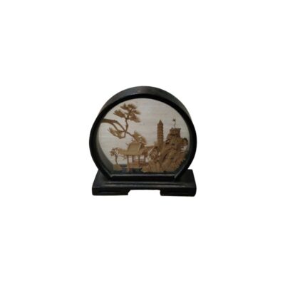 A miniature decorative object with a dark circular frame and a stand, characterised by an embossed diorama inside depicting a traditional oriental landscape with architectural structures, rock formations and stylised trees; available for hire for events, advertising, films and TV series