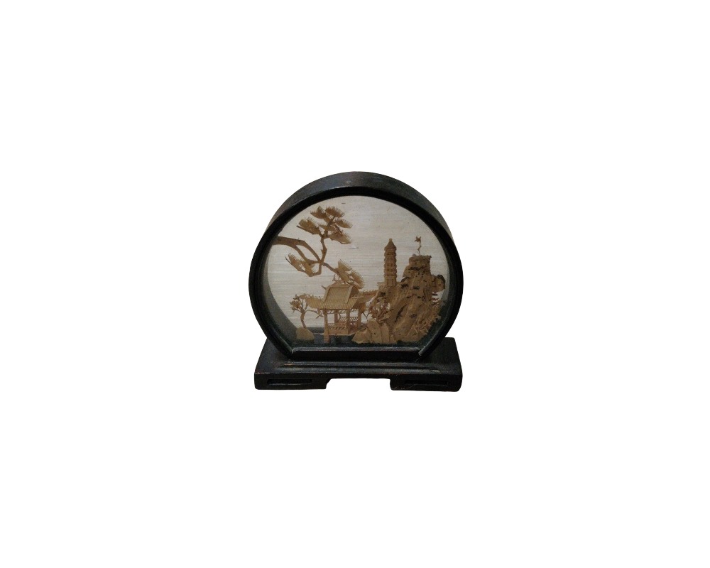 A miniature decorative object with a dark circular frame and a stand, characterised by an embossed diorama inside depicting a traditional oriental landscape with architectural structures, rock formations and stylised trees; available for hire for events, advertising, films and TV series