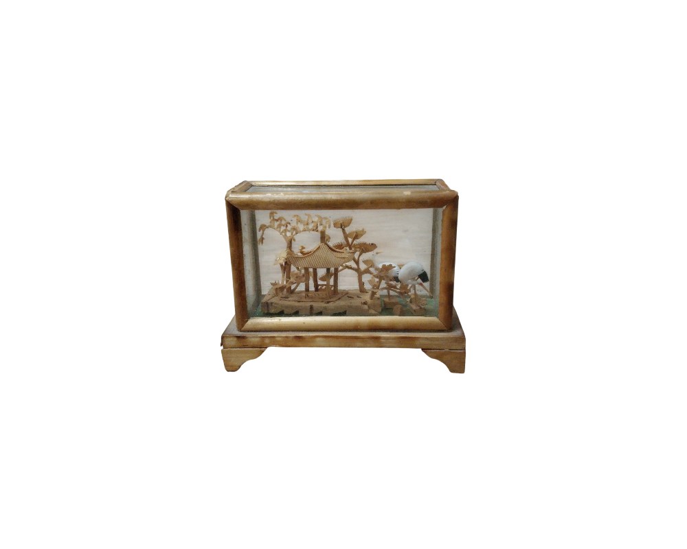 A small rectangular display case housing a delicate, handcrafted diorama, made primarily from carved cork. The scene recreates a traditional oriental landscape featuring a pavilion, stylised trees and bird figures, protected by glass panels and a wooden frame. It is a decorative piece of great detail and craftsmanship, designed to be displayed as a collector’s item that captures a natural scene in miniature. Available for hire for events, advertising, films and TV series.
