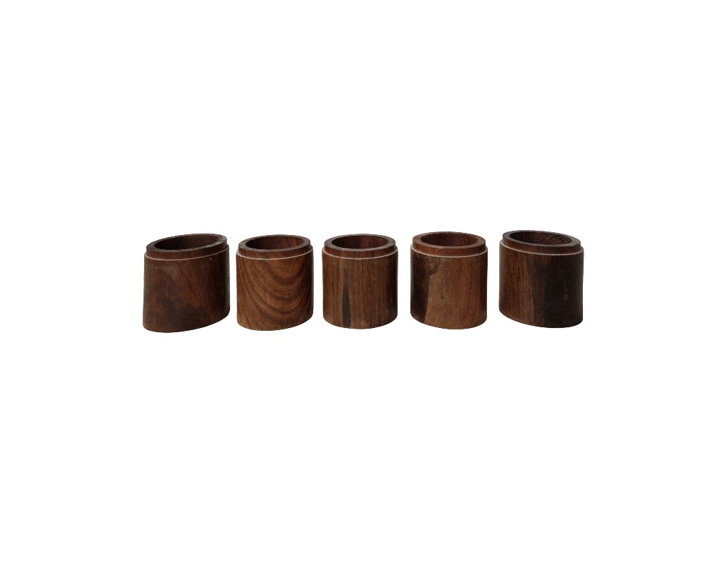 The set includes five cylindrical napkin rings made of carved wood, characterised by a polished finish that highlights the natural grain and warm tones of the material. Available for hire for events, advertising, films and TV series.