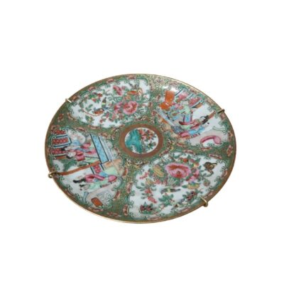 A decorative porcelain plate featuring intricate ornamentation divided into panels. The surface alternates between depictions of human figures in everyday or courtly scenes and detailed floral and botanical motifs, all framed by a background decorated with green patterns. Available for hire for events, advertising, films and TV series.