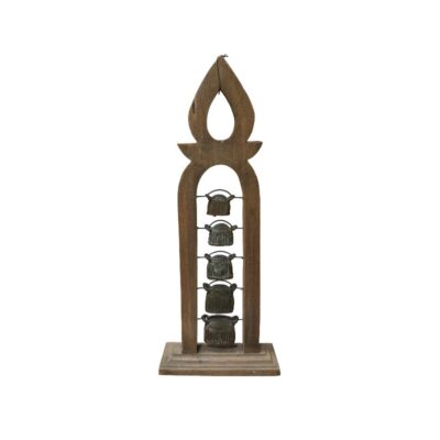 Objeto decorativo compuesto por una estructura vertical de madera tallada con una forma estilizada, que sostiene una serie de pequeñas campanas metálicas dispuestas en línea. La pieza destaca por su diseño artesanal y su marcada estética tradicional, funcionando como un elemento ornamental de sobremesa con un carácter rústico y cultural, ideal para quienes buscan integrar piezas con un toque étnico o histórico en su decoración.