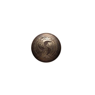 A circular medallion made of dark wood, with a metal inlay at its centre featuring a relief design depicting three intertwined figures; available for hire for events, advertising, films and TV series
