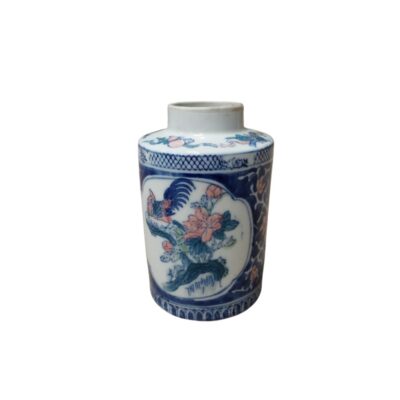 A cylindrical porcelain jar, characterised by its compact shape and polychrome decoration. The piece features central panels depicting a stylised bird accompanied by flowers, using a colour palette that combines cobalt blue with reddish tones; hire for events, advertising, films and TV series