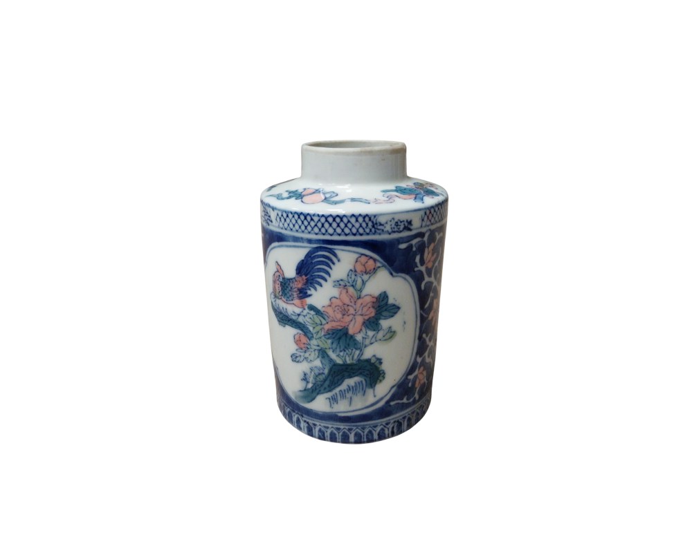 A cylindrical porcelain jar, characterised by its compact shape and polychrome decoration. The piece features central panels depicting a stylised bird accompanied by flowers, using a colour palette that combines cobalt blue with reddish tones; hire for events, advertising, films and TV series
