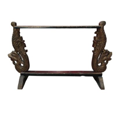 A display stand crafted from wood, featuring two side supports carved with dragon figures in relief and a finish that suggests a weathered, antique appearance. The design comprises a base, two decorative pillars and an upper crossbar, forming an ideal frame for displaying objects such as swords, fans or calligraphy pieces. It is a handcrafted piece with a distinctively oriental aesthetic, which lends presence and sophistication as a decorative centrepiece. Available for hire for events, advertising, films and TV series.