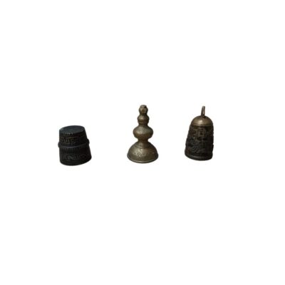 conjunto está compuesto por tres pequeños objetos metálicos de tonos oscuros y envejecidos, que incluyen un dedal o elemento cilíndrico con bandas grabadas, una pieza con forma de estupa o remate escalonado alquiler para eventos, publicidad, peliculas y series