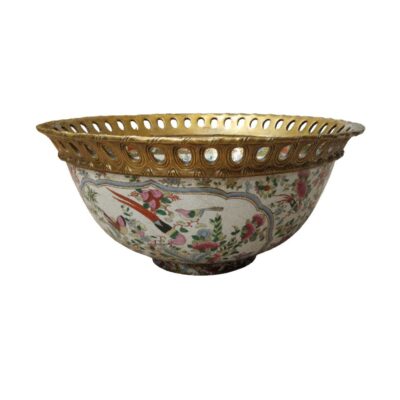 El cuerpo presenta un intrincado patrón floral con motivos de aves en tonos vibrantes, creando un contraste armonioso con su característico borde dorado de estilo calado. Este centro de mesa no solo es una pieza funcional, sino un elemento decorativo de gran valor estético, ideal para quienes buscan añadir un toque de distinción, historia y finura clásica a su decoración interior.