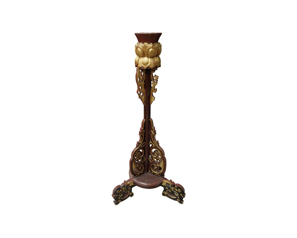 andelabro vertical de madera con acabados en tonos oscuros y dorados, caracterizado por una estructura elaborada con tallas caladas, una sección superior esculpida en forma de flor de loto y una base trípode estable alquiler para eventos, publicidad, peliculas y series