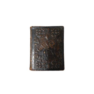 An antique hardback notebook with a dark leather cover, featuring intricate hand-embossed floral motifs and a central figure of a seated person set against a detailed background; available for hire for events, advertising, films and TV series