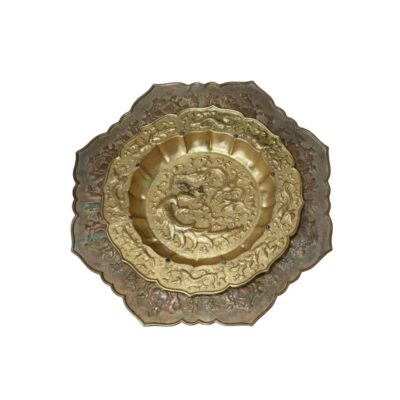 conjunto está compuesto por dos platos metálicos de bordes lobulados que se superponen, destacando un plato exterior de tono oscuro con grabados florales y un plato interior dorado y más pequeño alquiler para eventos, publicidad, peliculas y series