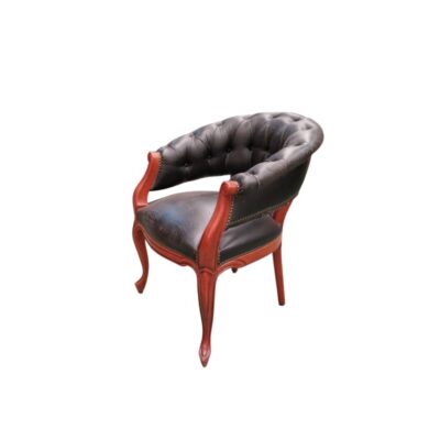 Sillón de escritorio estilo inglés Chesterfield, fabricado con cuero negro capitoné y una estructura de madera tallada, presenta un diseño clásico con respaldo curvo y reposabrazos integrados alquiler para eventos, publicidad, peliculas y series