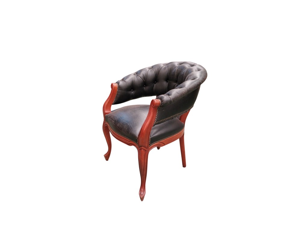 Sillón de escritorio estilo inglés Chesterfield, fabricado con cuero negro capitoné y una estructura de madera tallada, presenta un diseño clásico con respaldo curvo y reposabrazos integrados alquiler para eventos, publicidad, peliculas y series