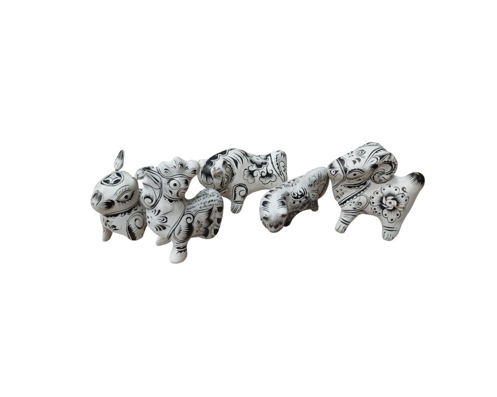 figuras escultóricas que representan a diversos animales de formas estilizadas, elaboradas en un material de tono claro y decoradas minuciosamente con intrincados motivos florales y geométricos pintados en color negro alquileres para eventos, publicidad, peliculas y series
