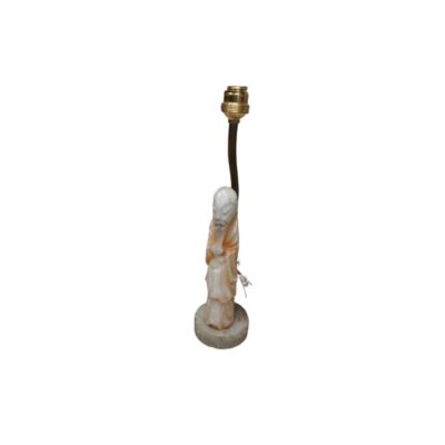 lámpara de sobremesa estructurada a partir de una figura esculpida que representa a un anciano sabio con túnica tradicional en tonos marfil y ámbar, montada sobre una base circular y equipada con un vástago y portalámparas metálico superior alquiler para eventos, publicidad, peliculas y series