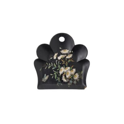 bandeja decorativa de superficie oscura y contorno lobulado, caracterizada por un orificio superior para colgar y una delicada pintura policromada en el centro que representa un ramo de margaritas blancas con hojas verdes y una pequeña mariposa alquiler para eventos, publicidad, peliculas y series