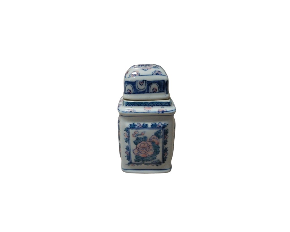 A small square porcelain jar with a matching lid. The piece features detailed cobalt blue decoration on a white background, accented with subtle touches of pink in the floral motifs. Available for hire for events, advertising, films and TV series.