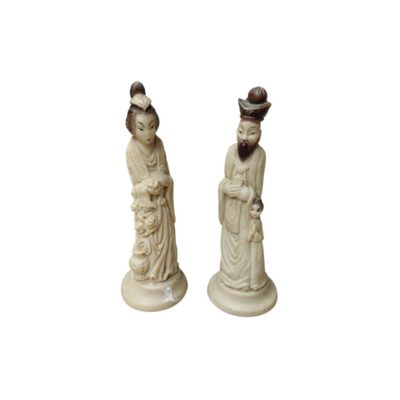 A pair of decorative pieces depicting two human figures dressed in traditional attire, carved from a material that mimics the appearance of ivory; available for hire for events, advertising, films and TV series