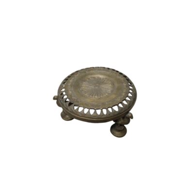 A circular metal stand with an aged finish, characterised by a concave surface design decorated with a central embossed motif of a rosette or rays, a perforated rim with openings, and three short sculpted legs; available for hire for events, advertising, films and TV series