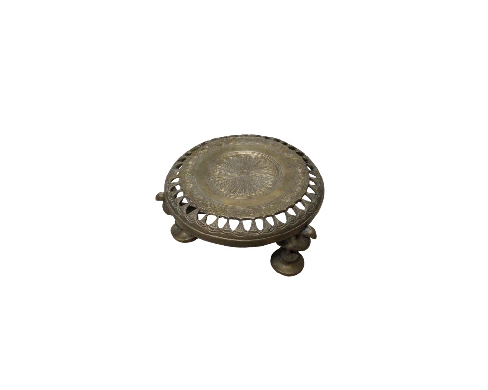 A circular metal stand with an aged finish, characterised by a concave surface design decorated with a central embossed motif of a rosette or rays, a perforated rim with openings, and three short sculpted legs; available for hire for events, advertising, films and TV series