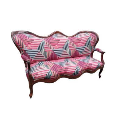 A 19th-century sofa in the Elizabethan or Louis XV style, featuring a carved wooden frame and modern geometric upholstery in shades of pink and grey; available for hire for events, advertising, films and TV series