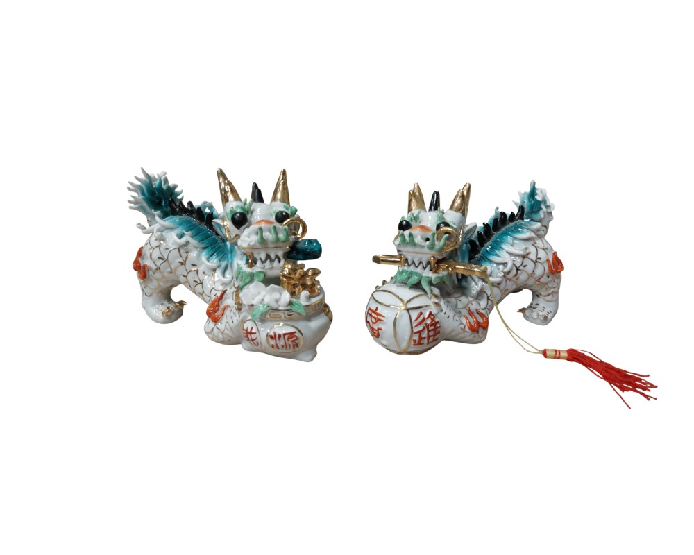 dos figuras de porcelana que representan al Qilin, una criatura mítica de la mitología oriental símbolo de prosperidad y buena fortuna. Las estatuillas están finamente detalladas con esmaltes en tonos blanco, verde y dorado alquiler para eventos, publicidad, peliculas y series