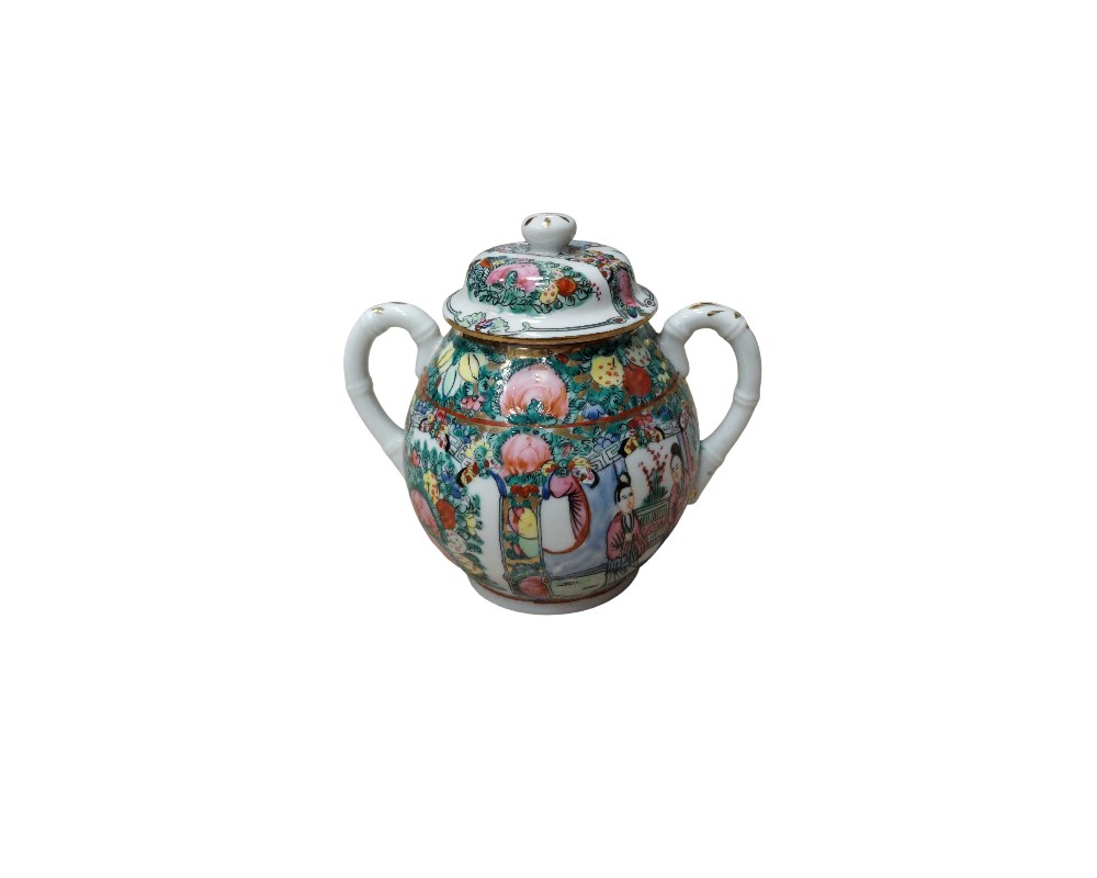 Porcelain sugar bowl with lid, decorated in the traditional ‘Rose Medallion’ style. The piece has a rounded shape with two stylised side handles that mimic the texture of bamboo. Available for hire for events, advertising, films and TV series.