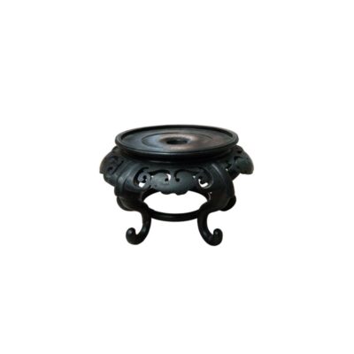 A decorative base, commonly known as a plinth, crafted from dark wood with a finish that highlights its handcrafted quality. It features a circular design with a flat upper rim for displaying objects, decorated with intricate openwork scrolls and stylised plant motifs, supported by curved legs that lend it elegance and stability. Available for hire for events, advertising, films and TV series.