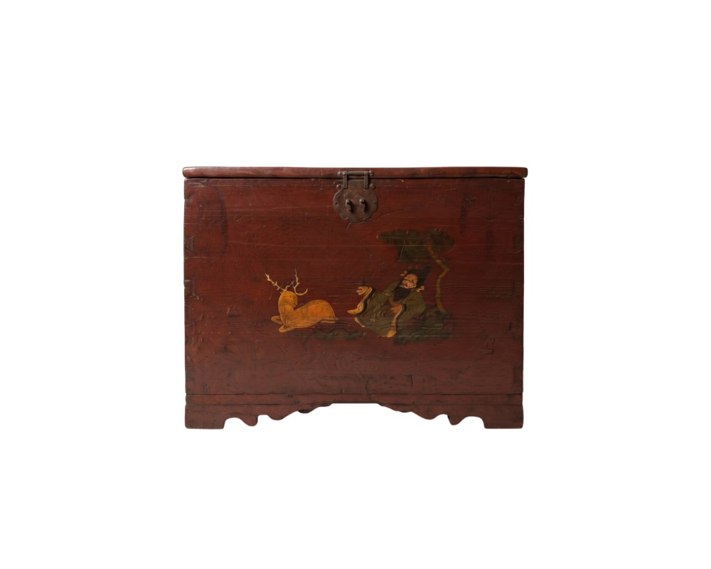 a large wooden chest, characterised by a dark reddish finish that highlights the natural grain of the wood. The front of the hinged lid is decorated with a painted scene depicting a figure seated beside a stag, a traditional iconographic motif that evokes serenity and longevity
