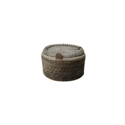 A circular wooden box with a rustic finish and aged tones, characterised by a body and a snug-fitting lid decorated with intricate, hand-carved reliefs featuring geometric patterns, braided bands and floral motifs. Available for hire for events, advertising, films and TV series.
