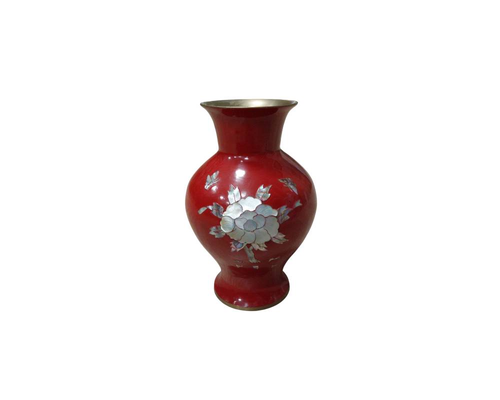 A vase with a rounded body and a glossy finish in a striking shade of red, decorated in the centre with a delicate mother-of-pearl inlay depicting an open flower alongside leaves and butterflies; available for hire for events, advertising, films and TV series