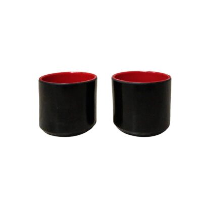 tazas de diseño cilíndrico y líneas limpias, con un acabado exterior de color negro brillante y un contraste vibrante en tono rojo en su interior alquiler para eventos, publicidad, peliculas y series