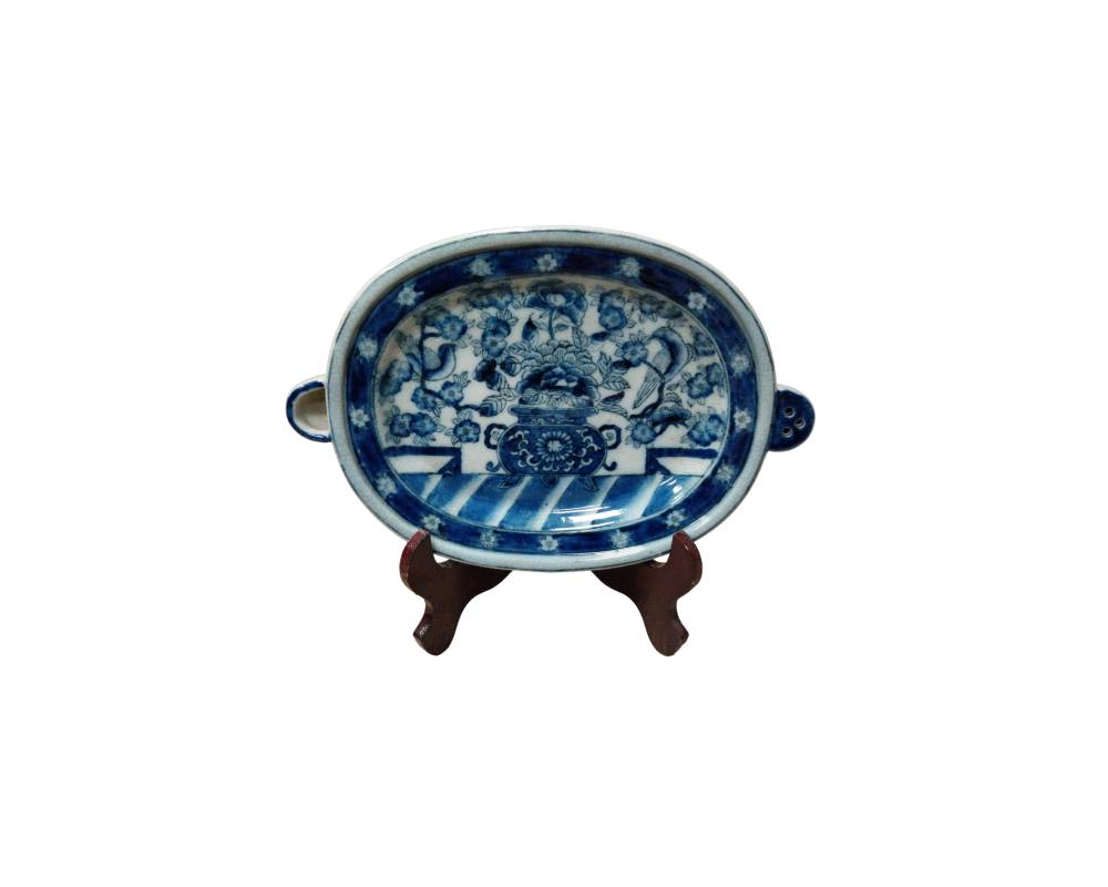 bandeja ovalada de porcelana decorada con la tradicional técnica azul sobre fondo blanco, presentando un motivo central detallado de paisajes, recipientes ceremoniales y elementos florales alquiler para eventos, publicidad, peliculas y series
