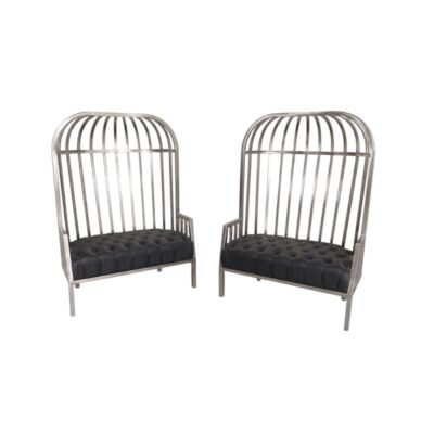 Se distingue por una estructura metálica alta que simula los barrotes de una jaula y un asiento tapizado en color oscuro con técnica de capitoné, combinando un estilo industrial con elegancia decorativa alquiler para eventos, publicidad, peliculas y series