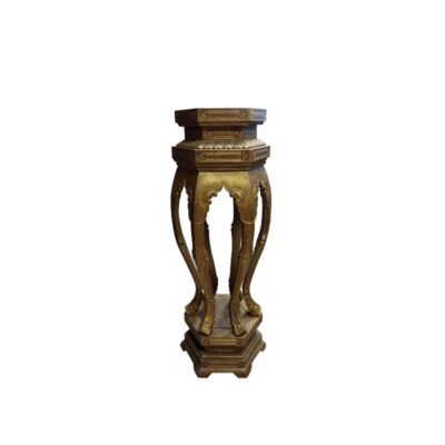 A tall pedestal with a patina in shades of gold and dark colours, characterised by a polygonal top platform, stylised curved legs with ornamental details and a matching solid base; available for hire for events, advertising, films and TV series